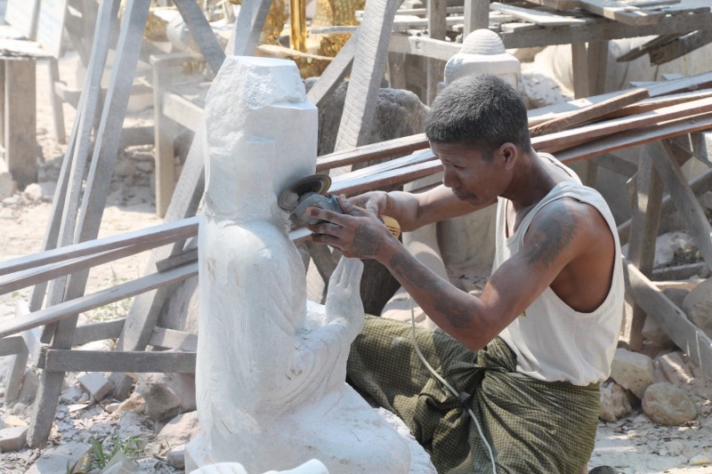 Ein Mann beim Schleifen einer Buddha-Statue